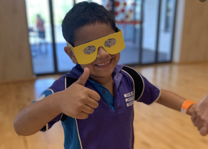 Young student wearing simulation glasses smiling at the camera giving a thumbs up